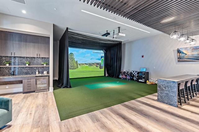 playroom with beverage cooler, golf simulator, and wood finished floors