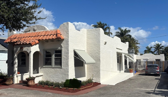 view of home's exterior featuring a tiled roof, fence, and stucco siding