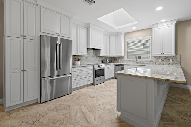 kitchen with a skylight, stainless steel appliances, tasteful backsplash, visible vents, and a peninsula