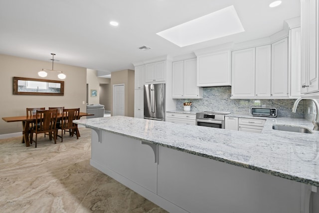 kitchen featuring visible vents, white cabinets, a peninsula, stainless steel appliances, and a sink