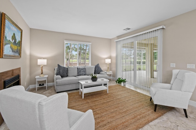 living area with a glass covered fireplace, visible vents, and baseboards