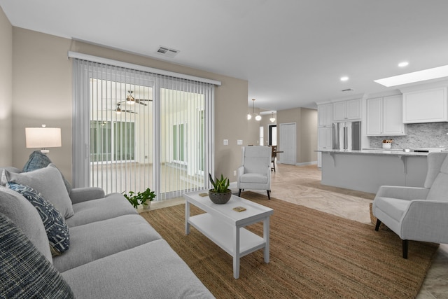 living room featuring baseboards, a skylight, visible vents, and recessed lighting