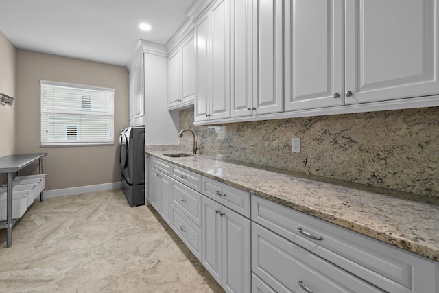 clothes washing area with independent washer and dryer, a sink, cabinet space, and baseboards