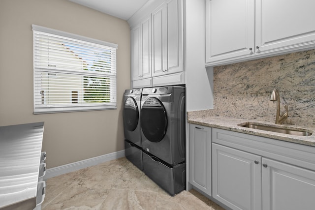 washroom with cabinet space, a sink, washer and clothes dryer, and baseboards