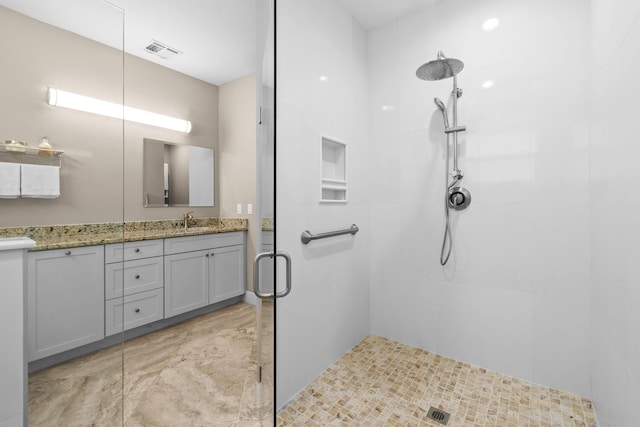 full bathroom featuring visible vents, tiled shower, and vanity