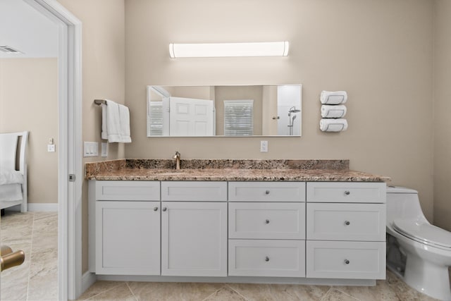 bathroom with toilet, vanity, visible vents, and baseboards