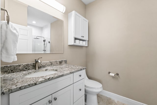 full bathroom with vanity, a shower stall, toilet, and baseboards