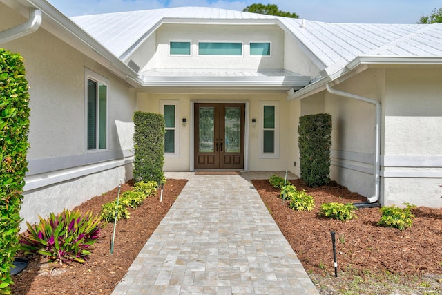 property entrance with stucco siding, metal roof, and french doors