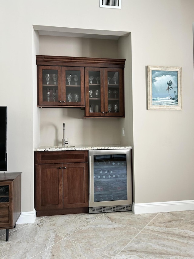 bar featuring wine cooler, a sink, visible vents, baseboards, and indoor wet bar