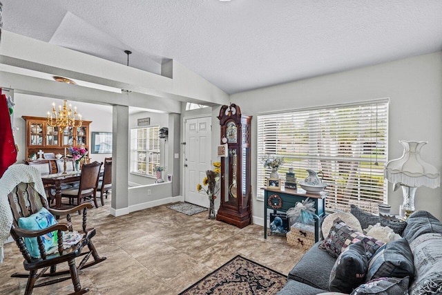 living area featuring a textured ceiling, baseboards, vaulted ceiling, and a notable chandelier