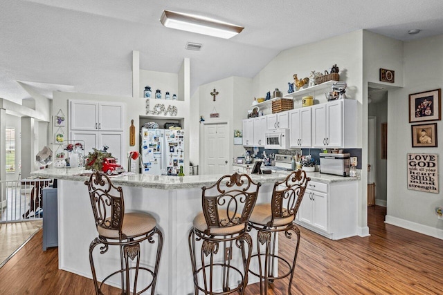 kitchen featuring white appliances, a breakfast bar area, white cabinets, and wood finished floors