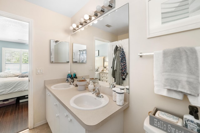 bathroom featuring wood finished floors, visible vents, a sink, and ensuite bathroom