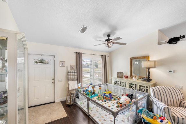 bedroom featuring a textured ceiling, wood finished floors, visible vents, baseboards, and vaulted ceiling