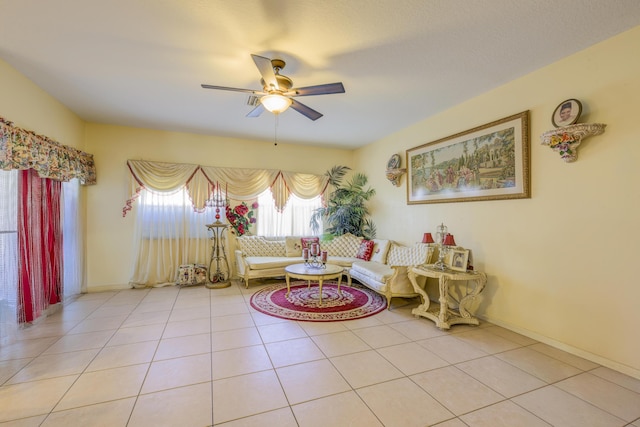 living area featuring a ceiling fan, light tile patterned flooring, and baseboards