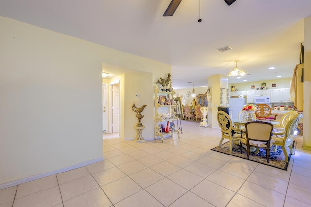 dining room with light tile patterned floors, baseboards, visible vents, and ceiling fan with notable chandelier