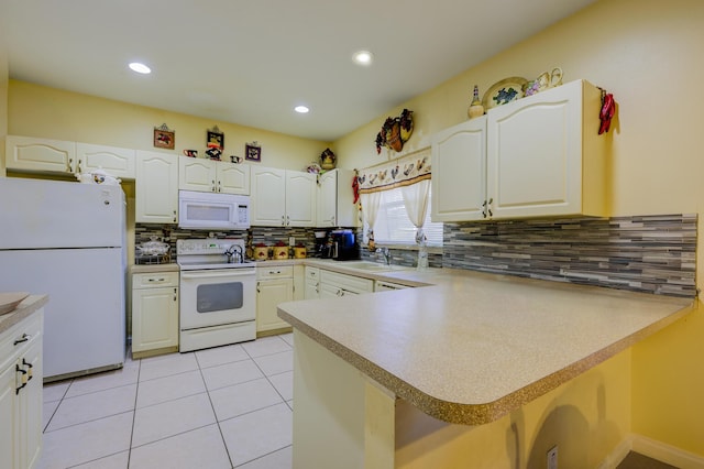 kitchen with light tile patterned flooring, a peninsula, white appliances, white cabinetry, and backsplash