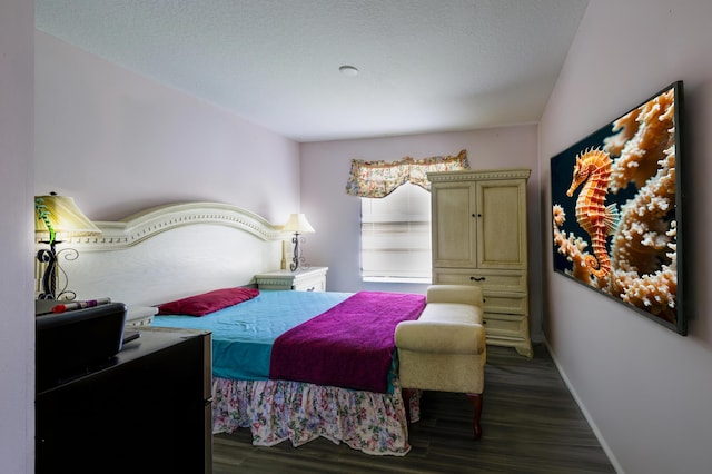 bedroom featuring a textured ceiling, baseboards, and wood finished floors