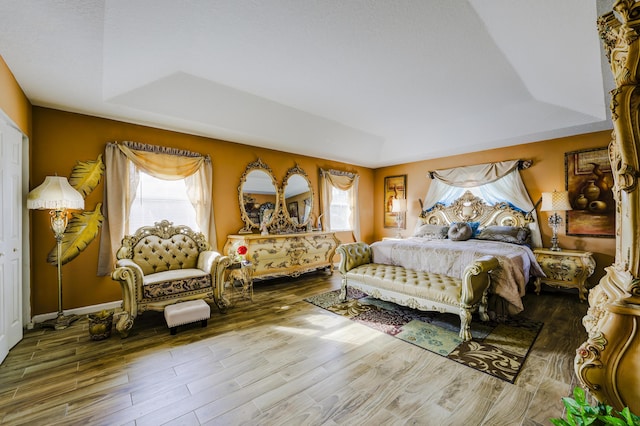 bedroom featuring a raised ceiling, wood finished floors, and baseboards