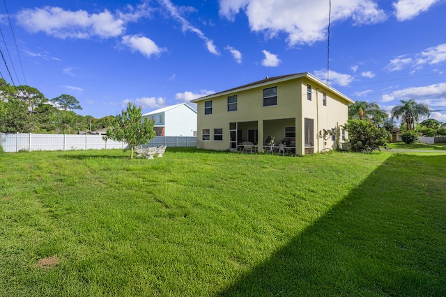 back of property featuring a yard, fence, and stucco siding