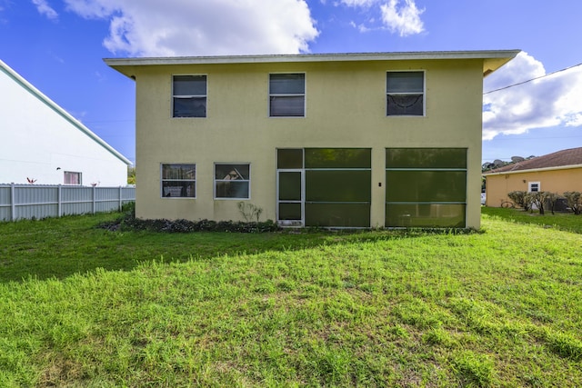 back of property featuring stucco siding, fence, and a yard