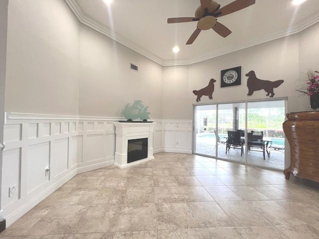 unfurnished living room with a wainscoted wall, visible vents, a decorative wall, ornamental molding, and a glass covered fireplace