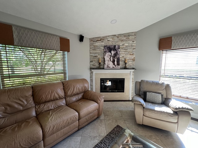 living room featuring tile patterned flooring, vaulted ceiling, a textured ceiling, and a glass covered fireplace