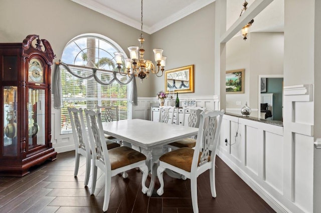 dining room featuring a wainscoted wall, a notable chandelier, a decorative wall, ornamental molding, and dark wood-type flooring