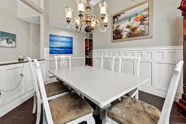 dining room with wood tiled floor, wainscoting, an inviting chandelier, and a decorative wall