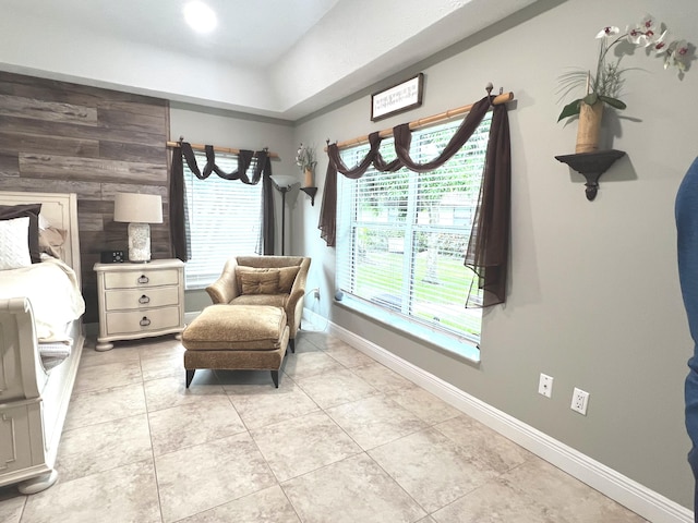 sitting room featuring wood walls, baseboards, and light tile patterned floors