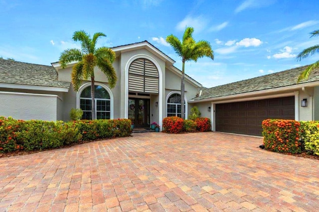 view of front of home featuring an attached garage, decorative driveway, and stucco siding