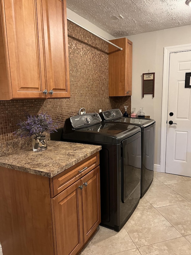 laundry room with cabinet space, a textured ceiling, washer and dryer, and light tile patterned flooring