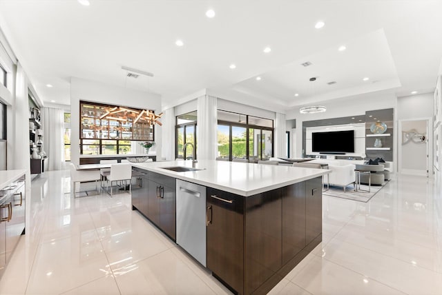 kitchen with a tray ceiling, a sink, stainless steel dishwasher, and modern cabinets