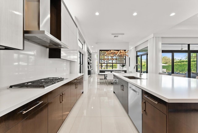 kitchen featuring stainless steel appliances, light countertops, a sink, and wall chimney exhaust hood