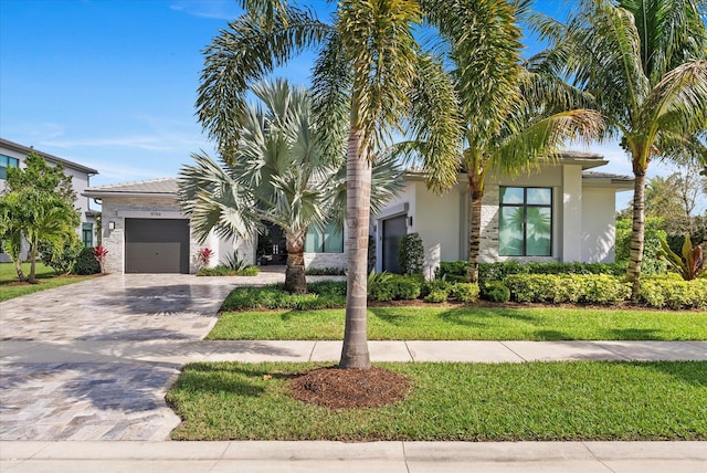 view of front of house featuring a garage, decorative driveway, a front yard, and stucco siding