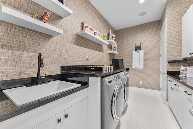 laundry area with washing machine and dryer, tile walls, a sink, and light tile patterned flooring