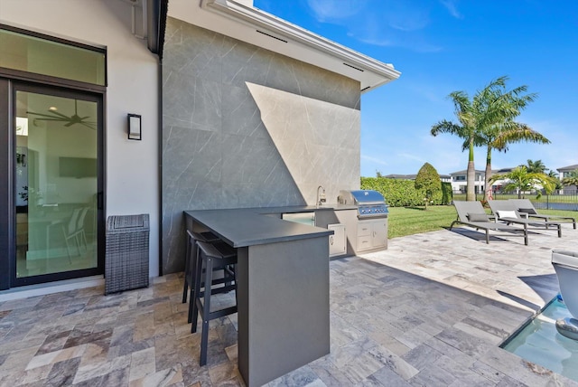 view of patio with area for grilling, an outdoor kitchen, and outdoor wet bar