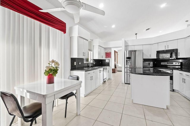 kitchen with light tile patterned floors, stainless steel appliances, dark countertops, and a kitchen island