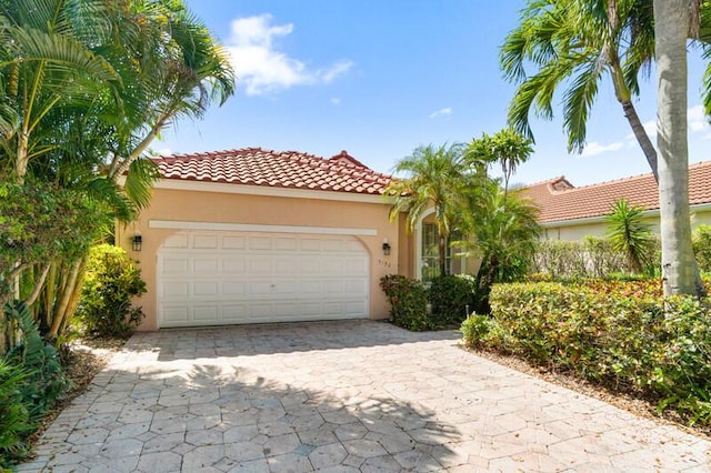 mediterranean / spanish-style house with an attached garage, a tile roof, and stucco siding