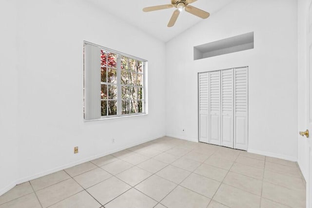 unfurnished bedroom featuring baseboards, a ceiling fan, vaulted ceiling, a closet, and light tile patterned flooring