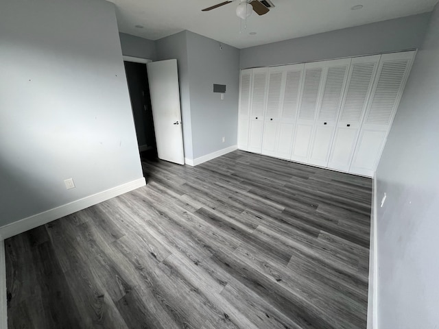 unfurnished bedroom featuring ceiling fan, a closet, baseboards, and wood finished floors