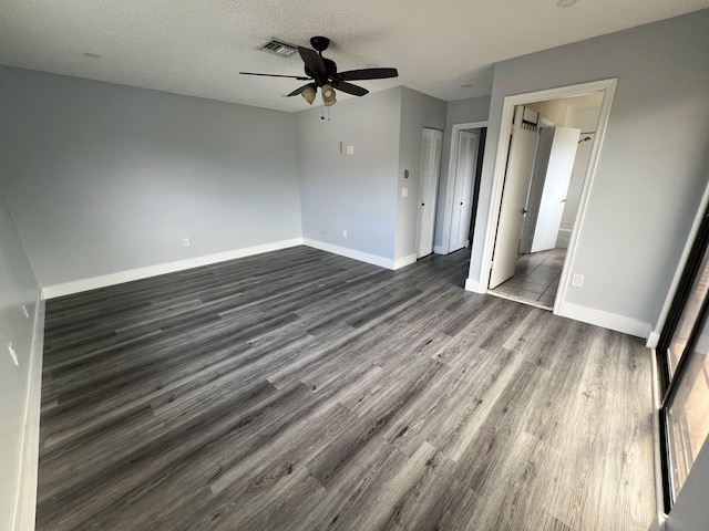 unfurnished bedroom with baseboards, a textured ceiling, visible vents, and dark wood-type flooring