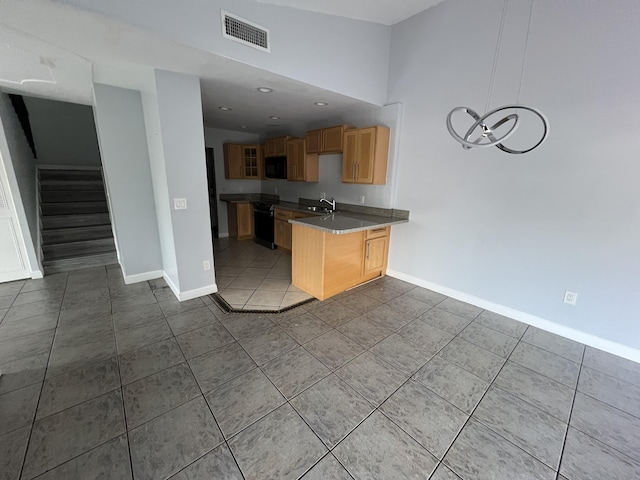 kitchen featuring black microwave, a peninsula, visible vents, baseboards, and tile patterned floors