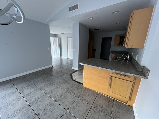 kitchen with light tile patterned floors, visible vents, open floor plan, vaulted ceiling, and a sink