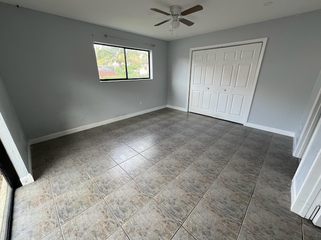 unfurnished bedroom with a ceiling fan, a closet, baseboards, and tile patterned floors