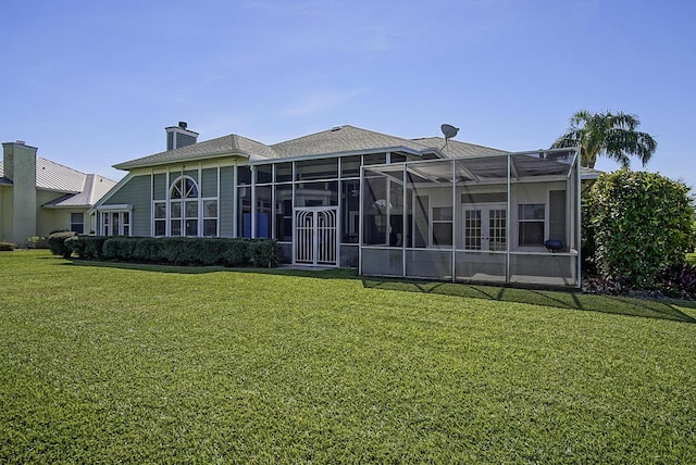 back of house featuring french doors, a lawn, and a chimney