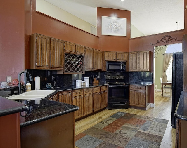 kitchen with a sink, decorative backsplash, black appliances, brown cabinetry, and dark countertops