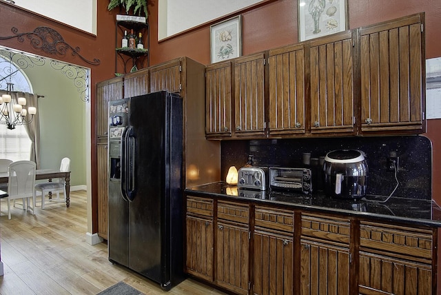 4408 Gator Trace Ln, Fort Pierce, FL 34982 - kitchen with black fridge with ice dispenser, dark countertops, light wood-type flooring, a chandelier, and decorative backsplash