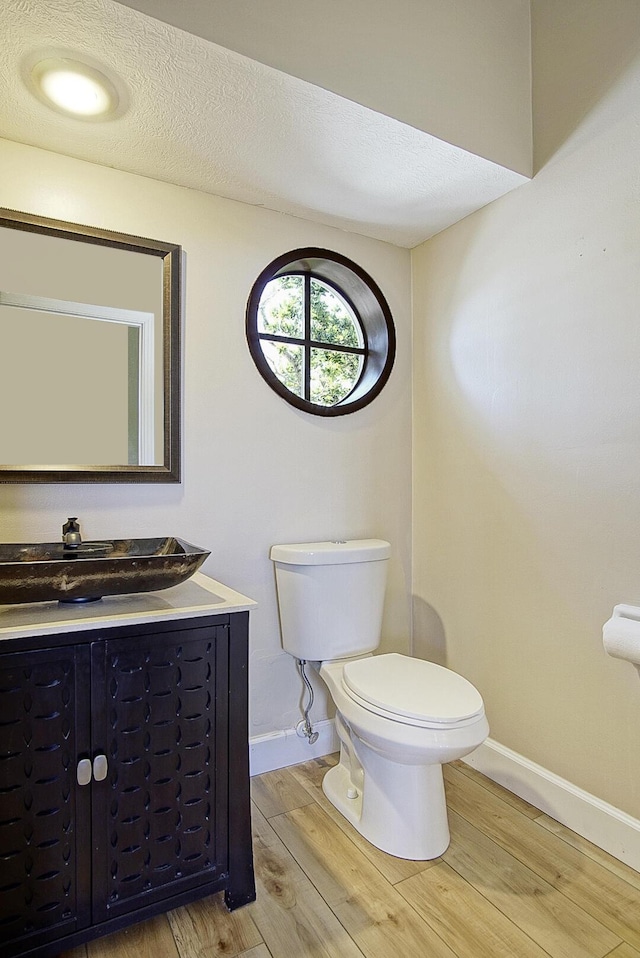 bathroom featuring baseboards, a textured ceiling, toilet, and wood finished floors