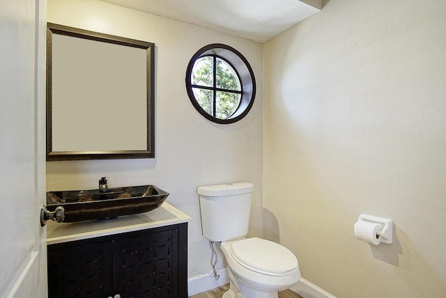 bathroom with vanity, toilet, and baseboards