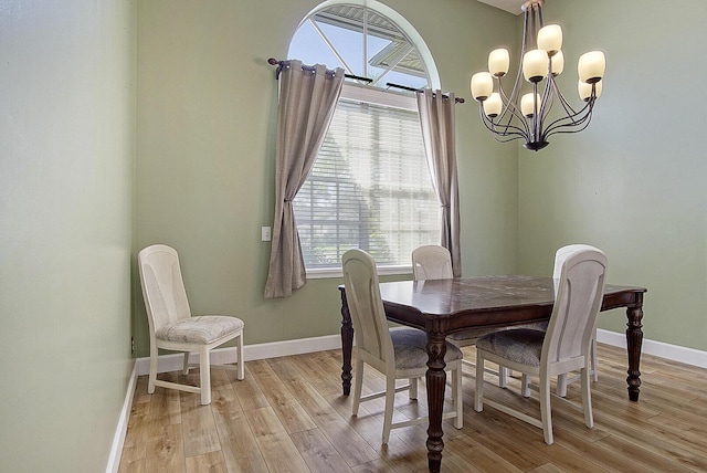 dining room with light wood finished floors, an inviting chandelier, and baseboards